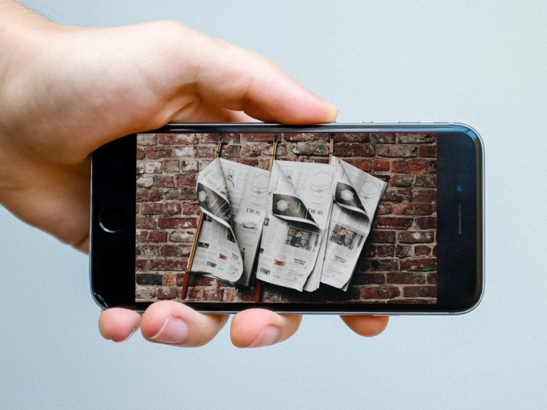 hand holding smartphone showing newspapers on screen