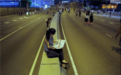 Woman reading the paper while sitting in the middle of the street